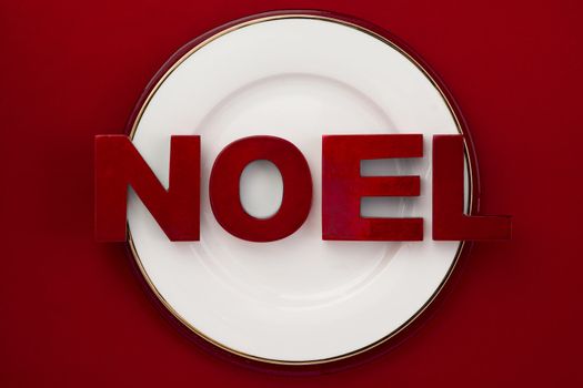 Image of white plate with word noel red background