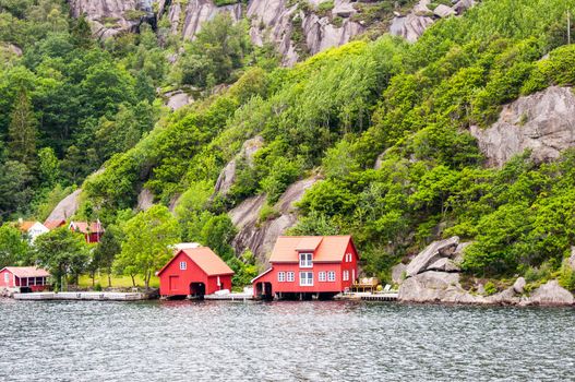 Red generic home next to fiord in Norway. Typical Nordic residential architecture.