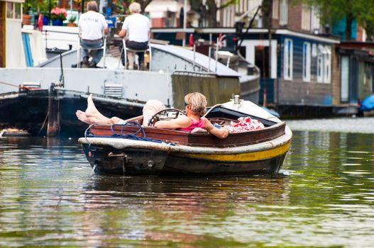 AMSTERDAM, JUNE 10: Motorboat with resting man on Amsterdam canal on June 10, 2011. Amsterdam has been called the "Venice of the North" for its more than one hundred kilometers of canals, about 90 islands and 1,500 bridges.