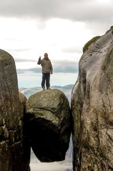 Man standing on Kjeragbolten in Norway. Stone between two rocks