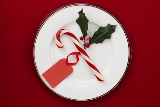 Image of candy cane with red tag in a plate in red background
