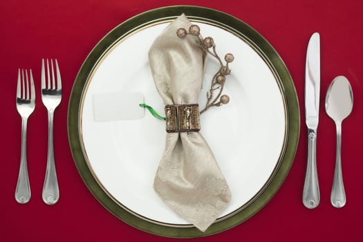 Overhead shot of plate and silverware on red table cloth, white napkin in plate with an empty card.