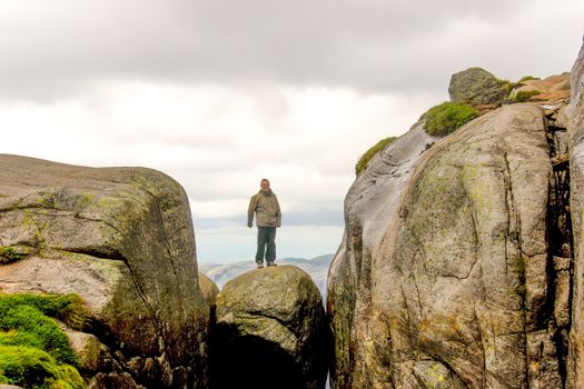 Man standing on top of Kjerag rock (kjeragbolten)