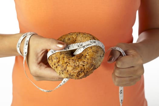 Close up image of hand holding bread with measuring tape against white background
