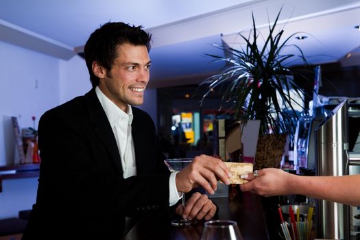 Man at the bar paying with gold credit card