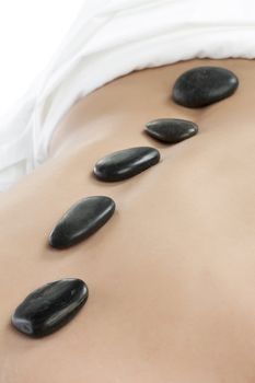 Hot stone massage on the back of the woman