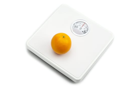 Weighing scale and orange fruit on white