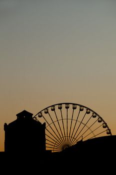 Silhouette image of ferris wheel at sunset against clear majestic sky.