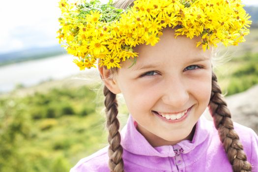 Portrait of a little girl with a wreath of dandelions