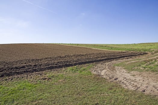 rural brown farm land field with blue and cloudless sky