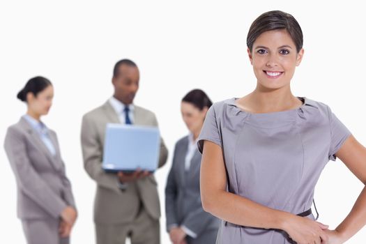 Woman with hands on her hips with business team in the background against white background