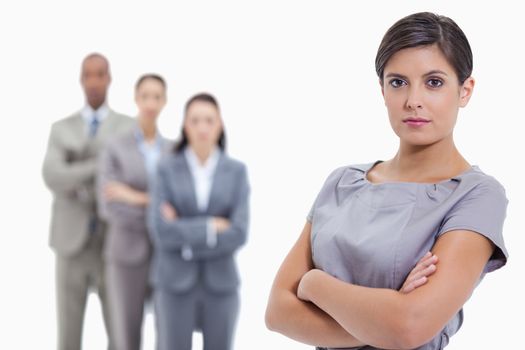 Close-up of a serious businesswoman and a team crossing their arms in background