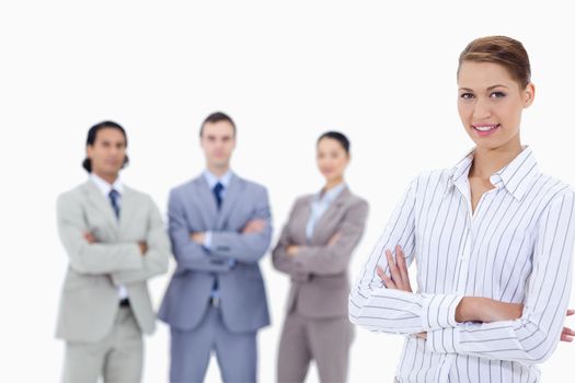 Close-up of a secretary smiling with business people crossing their arms in background