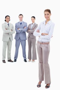 Secretary smiling and crossing her arms with happy business people behind her against white background