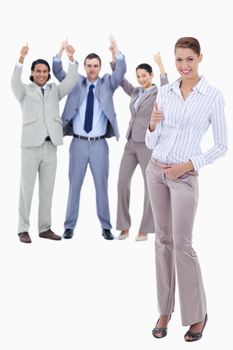 Secretary in foreground and business people with their thumbs up against white background