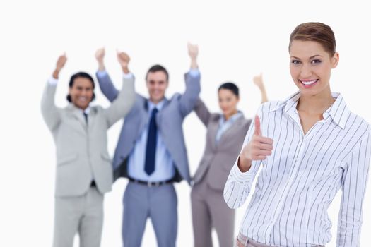 Close-up of a woman smiling and approving with enthusiastic business people with their thumbs up in background