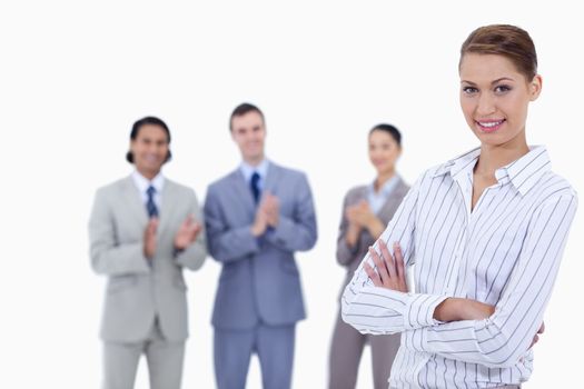 Close-up of a woman crossing her arms with business people applauding while watching her against white background