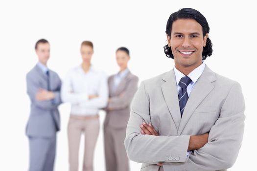 Close-up of a businessman smiling and crossing his arms with serious people in background 