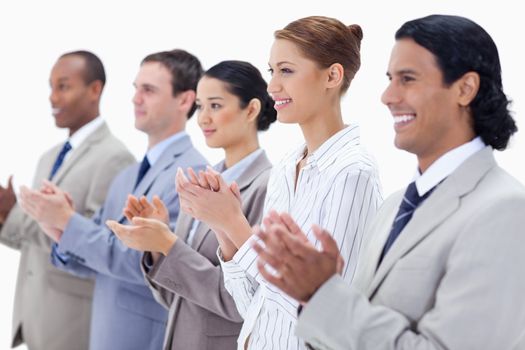 Close-up of business people smiling and applauding with focus on the first three people against white background