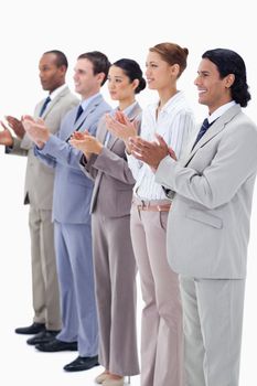 People dressed in suits smiling and applauding while looking towards the left side against white background