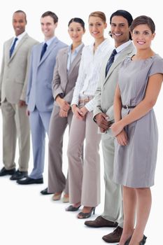 Co-workers smiling looking straight with focus on the first two people against white background