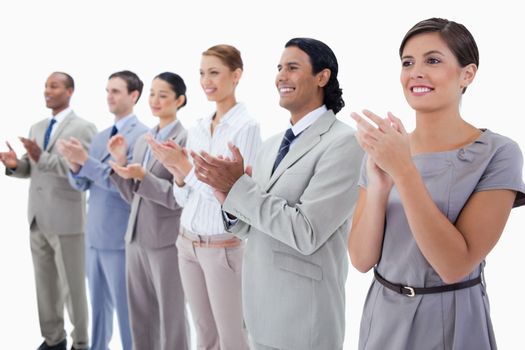 Close-up of colleagues smiling and applauding with focus on the first two people against white background