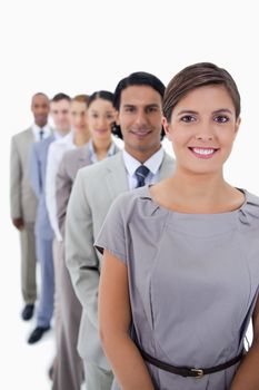 Close-up of colleagues in a single line smiling and looking straight with focus on the first woman against white background