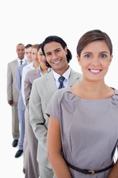 Close-up of co-workers in a single line smiling and looking straight with focus on the first man against white background