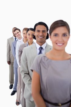 Close-up of workmates in single line smiling and looking straight with focus on the second man against white background