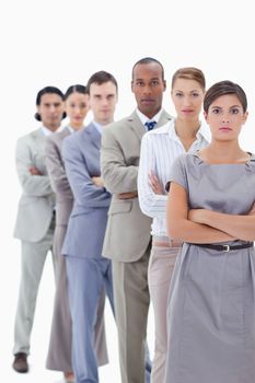 Close-up of a serious business team in a single line crossing their arms with focus on the first woman