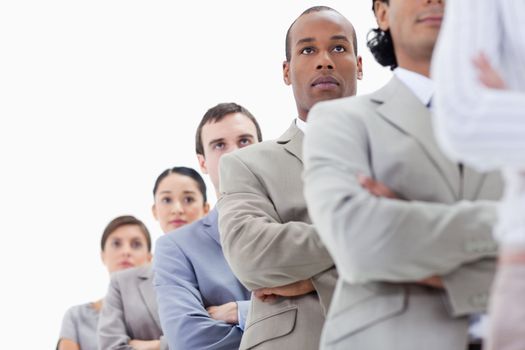 Low-angle shot of a serious business team crossing their arms in a single line with focus on the second man