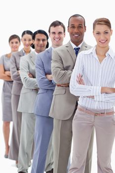 Smiling workmates dressed in suits crossing their arms in a single line with focus on the first man