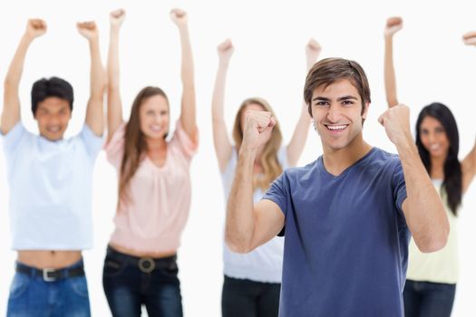 Man clenching his fists with people behind him raising their arms against white background