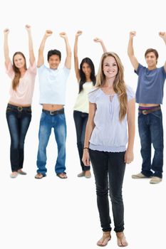 Woman smiling with people with their arms raised behind her against white background