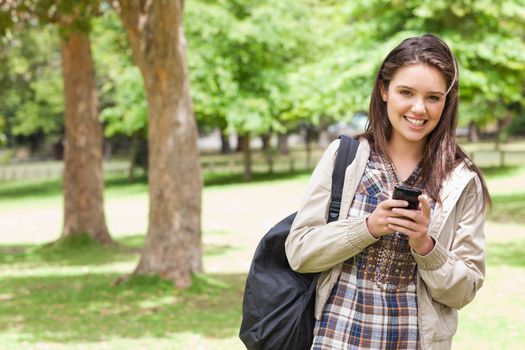 Portrait of a young student using a smartphone in a park