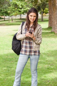 Young student posing while using a smartphone in a park