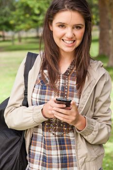 Portrait of a young student using a smartphone in a park