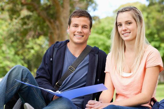 Portrait of a tutor helping a teenager to revise in a park