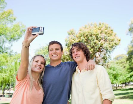 Close-up of three smiling students taking a pictures of themselves in a park