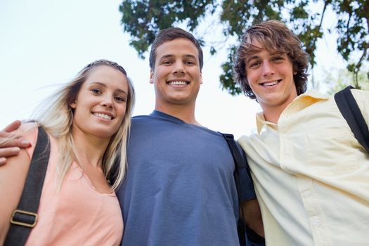 Low angle-shot of three students shoulder to shoulder in a park