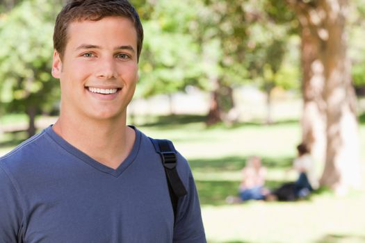 Portrait of a student smiling in a park with friends in background