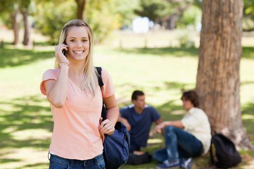 Portrait of a girl on the phone in a park with friends in background