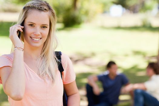 Close-up of a girl on the phone in a park with friends in background