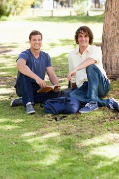 Portrait of two male students studying in a park