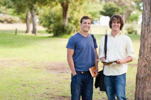 Portrait of two standing male students talking in a park