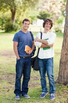 Portrait of two happy standing male students in a park