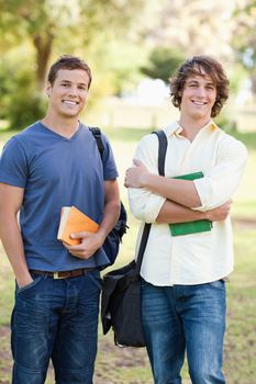 Portrait of two standing handsome students talking in a park