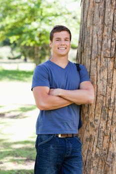 Portrait of a muscled student next to a tree in a park
