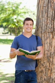 Portrait of a muscled young man holding a book in a park
