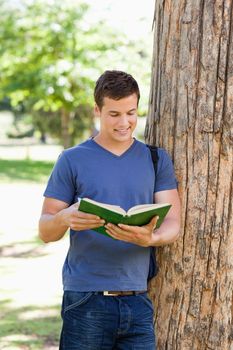 Muscled young man reading a book in a park